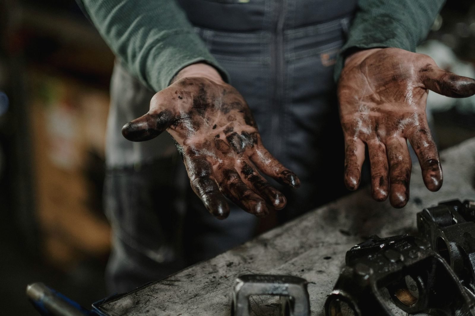 Two hands covered in engine grease held palms up