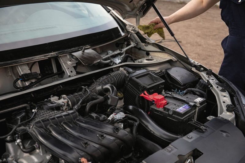 A car with the hood raised and the battery and engine exposed
