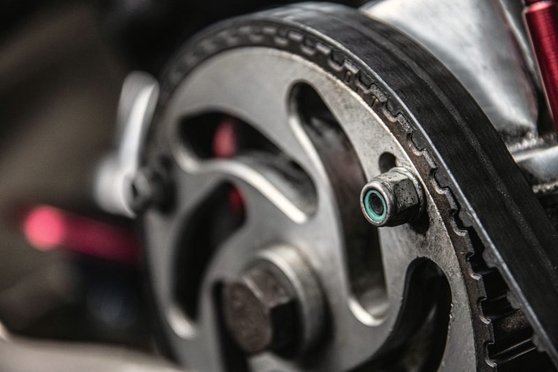 A toothed timing belt running over a metal cam sprocket